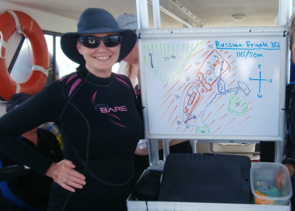 Divemaster on the dive boat with whiteboard drawing of the shipwreck
